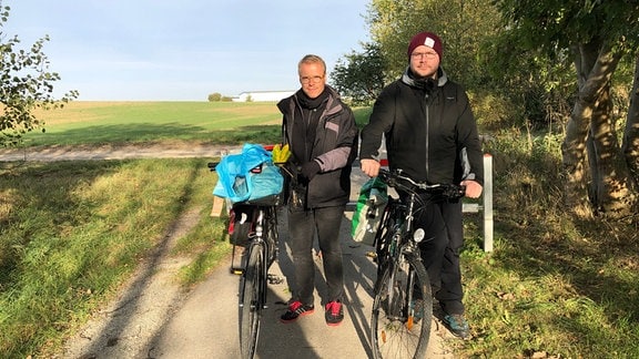 André Plaul und Leonard Schubert mit Fahrrädern auf einem schmalen Weg
