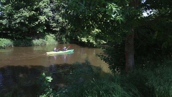 Zwei Personen fahren in einem Kanu auf einem Fluss.