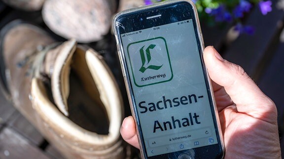 Das Logo des Lutherweges ist auf einem Smartphone auf der Internetseite des Pilgerweges zu sehen.