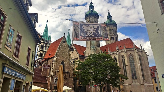Eine Banner hängt in einer Straße. Im Hintergrund ist der Naumburger Dom zu sehen. 