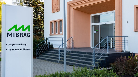 Vor dem Eingang eines Gebäudes steht ein Schild, das auf den Sitz der Mibrag hinweist. 