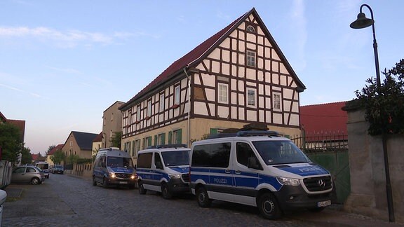 Mehrere Polizeiwagen vor einem Fachwerkhaus in Bornitz