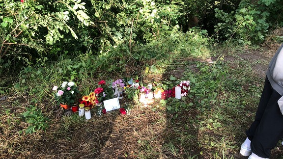 Blumen und Kerzen am Straßenrand erinnern an drei verunglückte Personen in der Nähe von Naumburg
