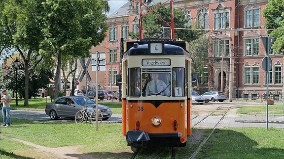 Eine alte Straßenbahn fährt bei sonnigem Wetter durch Naumburg.