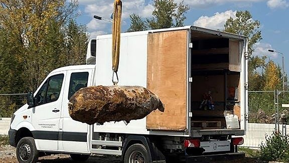 Die entschärfte Bombe hängt am Haken in der Luft und wird zum Abtransport verladen.