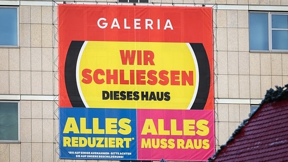 An der Fassade der Galeria Kaufhof in Halle hängt ein großes Transparent