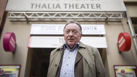 Peter Sodann, ein Mann steht vor einem Eingang, über dem neues theater steht.