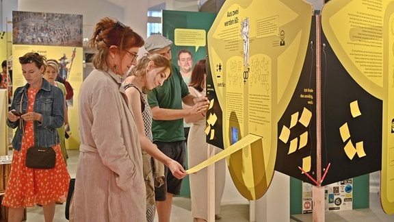 Besucher schauen sich Tafeln in einem Ausstellungsraum an.