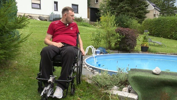 EIn Mann in einem Rollstuhl neben einem Pool.