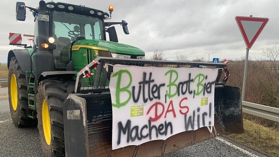 Ein Traktor an der Autobahn-Auffahrt der A143 bei Halle mit der Aufschrift: "Butter, Brot, Bier – das machen wir!"