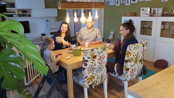 Eine vierköpfige Familie sitzt an einem Tisch mit ihrer Doula.