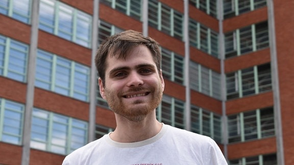 Erik Peuker, ein junger Mann mit Bart, lächelt in die Kamera.