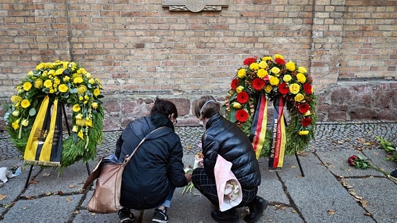 Menschen gedenken vor der Synagoge in Halle/Saale den Opfern des Halle-Attentats.