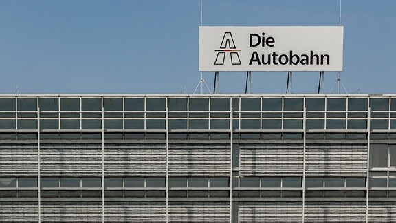 Auf dem Dach eines Gebäudes im Zentrum von Halle weist ein Schild auf einen Standort der Autobahn GmbH des Bundes hin.  