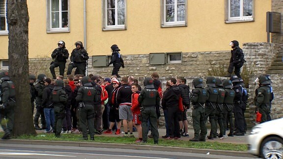 Große Gruppe von Menschen, darunter viele Polizisten in Uniform mit Helmen