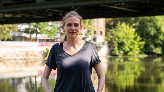 Maria Schubert, Sprecherin des Politik-Teams von Halle Zero, steht vor einer Brücke an der Saale.