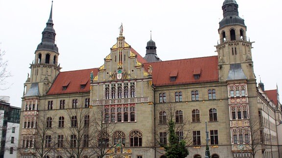 Das Landgericht Halle von außen mt grauer Fassade, rotem Dach, vier Stockwerken und zwei Türmchen links und rechts.