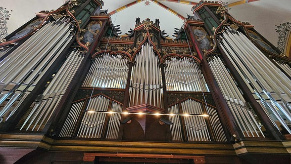 Eine große steht in einem Kirchenschiff, große Orgelpfeifen leuchten in der Sonne