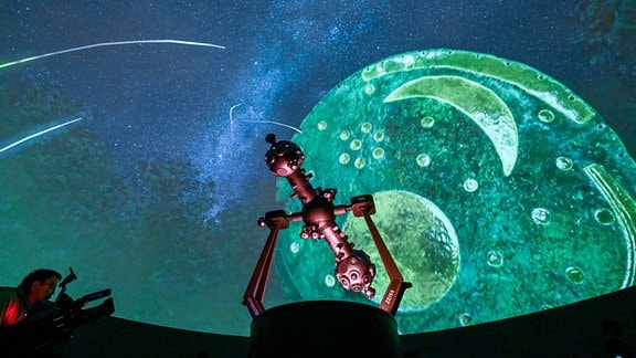 Eine Projektion der Himmelsscheibe von Nebra ist im Sternensaal des Planetariums hinter dem Projektor zu sehen. 