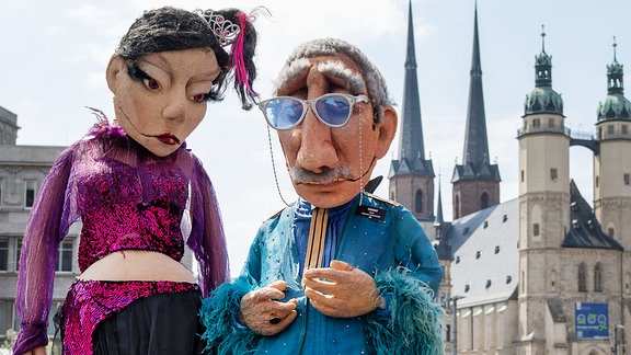 Vor Beginn einer Pressekonferenz des Puppentheaters Halle/Saale stehen zwei Großpuppen von Puppenbauerin Louise Nowitzki vor der Marktkulisse der Stadt.