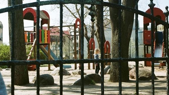 Kinder auf einem Spielplatz mit einem Zaun davor