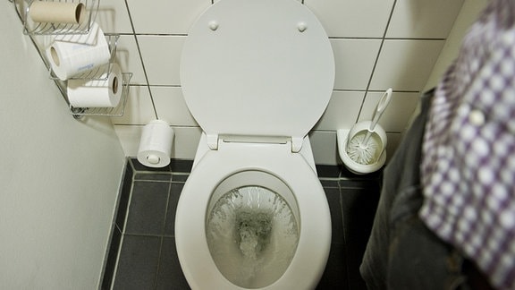 Ein Mann betätigt eine Toilettenspülung. 