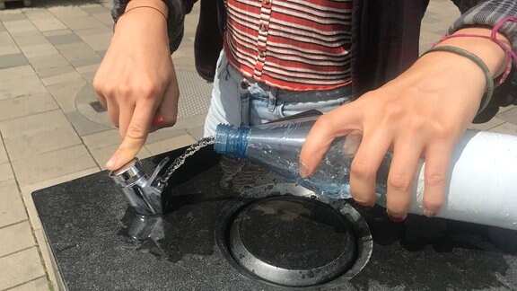 Eine Flasche wird am Trinkwasserbrunnen befüllt
