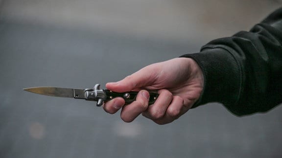 Männerhand mit einem verbotenen Springmesser 