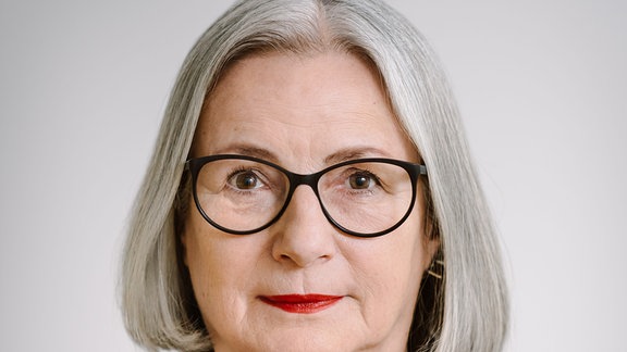 Ulrike Wünscher, eine Frau mit grauen Haaren und Brille, schaut in die Kamera