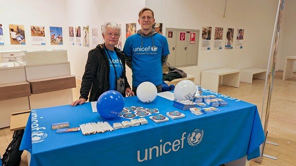 Zwei Personen stehen hinter einem Unicef-Stand.