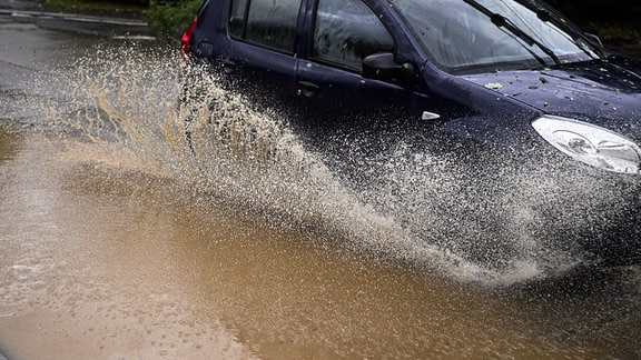  Ein Auto fährt nach heftigen Regenfällen auf einer von Hochwasser überschwemmten StraÃe. 