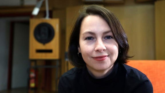 Jūratė Braginaitė, eine Frau sitzt in einem Sessel und lächelt in die Kamera