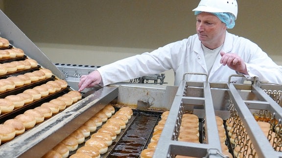 Ein Mitarbeiter überwacht ein Frittierbad mit "Berliner" Pfannkuchen in der Aryzta Bakeries Deutschland GmbH in Lutherstadt Eisleben (Sachsen-Anhalt), 2017.