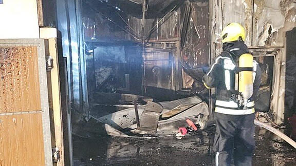 Ein Feuerwehrmann steht in einer ausgebrannten Fleischerei in Ummendorf.
