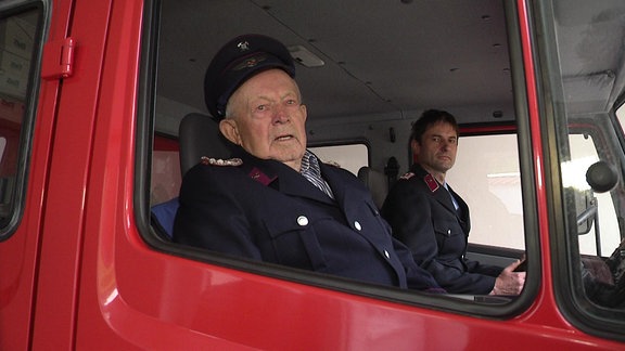 Feuerwehrmann Rudolf Stöckel sitzt in einem Löschfahrzeug.