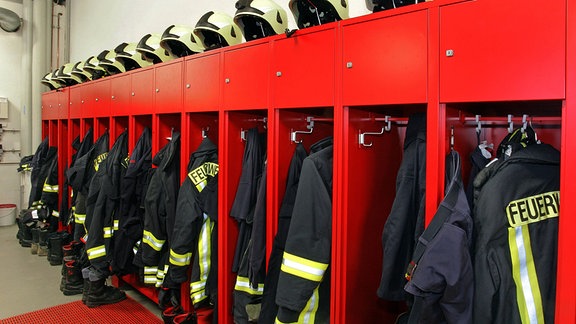 Feuerwehruniformen hängen in der Umkleide einer Feuerwehr.
