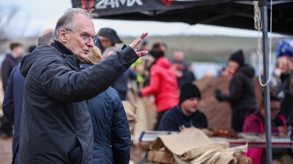 Rainer Haseloff (CDU), Ministerpräsident von Sachsen-Anhalt, reagiert auf einen Rufer bei der zentralen Sandsackbefüllungsanlage. 