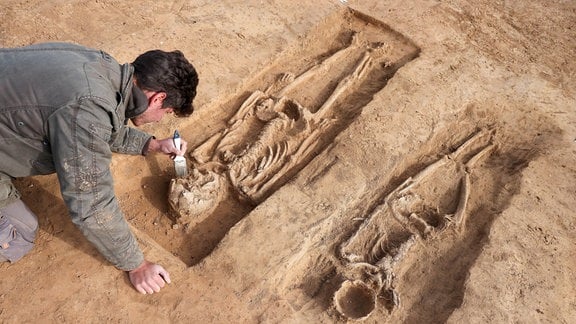 Ein Grabungsteilnehmer legt ein Grab aus der Karolingerzeit auf dem Gelände der Königspfalz Helfta frei.