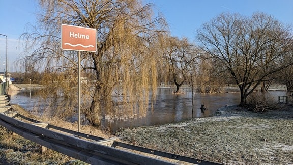 Ein Schild mit der Aufschrift "Helme" vor einer winterlichen Flusslandschaft