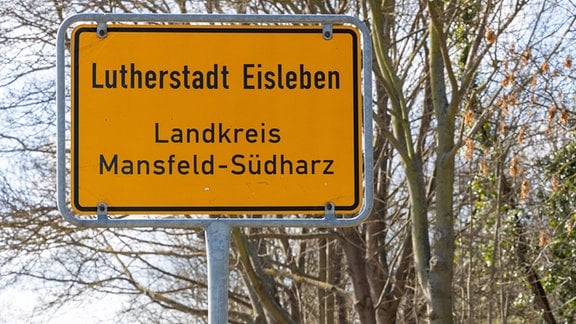 Zwei Schilder neben einer Straße weisen auf den Ortseingang der Lutherstadt Eisleben hin. 