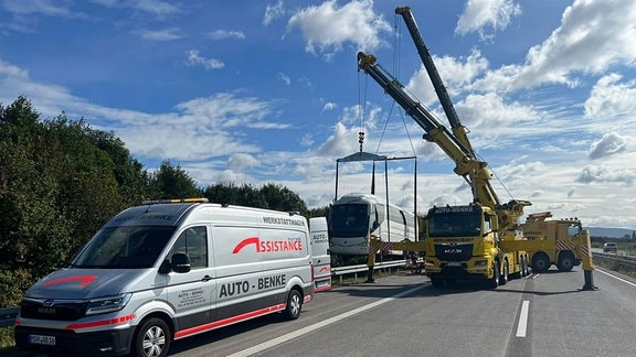 Zwei Schwerlastkräne heben den Reisebus aus dem Straßengraben.