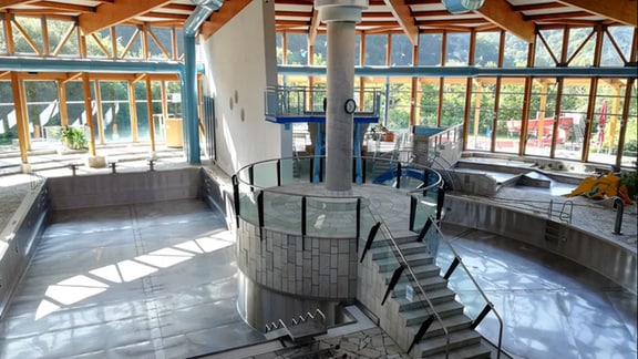 Blick in das leere Freizeitbad Thyragrotte: Licht scheint durch die runde Glasfassade in die Badelandschaft mit leeren Becken