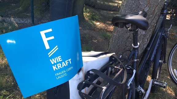 Ein blaues Fähnchen an einem Fahrrad mit der Aufschrift "F wie Kraft"