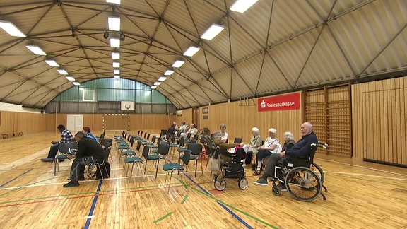 Mehrere Menschen in einer Sporthalle.