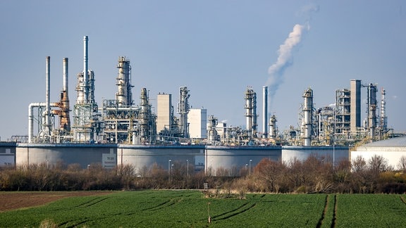 Hinter einem Tanklager im Chemiepark Leuna, ragen die Anlagen der Total-Raffinerie in die Höhe. 