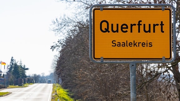 Das Ortseingangsschild von Querfurt steht neben einer Straße. 