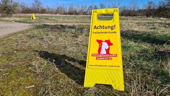 Ein gelbes Schild mit der Aufschrift: Achtung! Freilaufende Hunde.