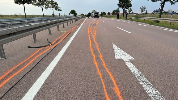 Orange gekennzeichnete Fahrspuren auf einer Fahrbahn nach einem Unfall.