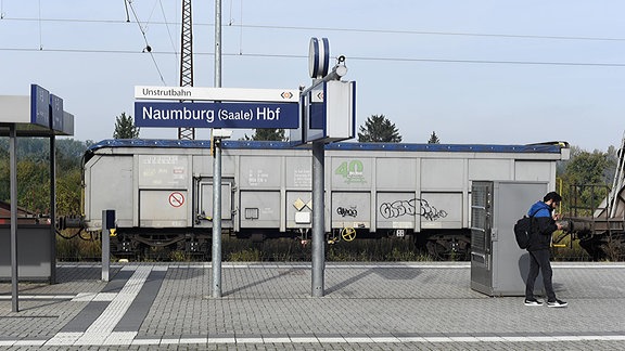 Im Bahnhof Naumburg (Saale) stehen Güterzugwaggons, davor ein Stationschild mit der Aufschrift Unstrutbahn und Naumburg.