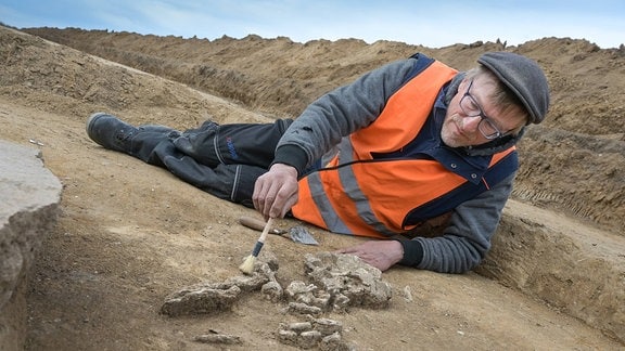 Ein Mann arbeitet an einem auf einer Baustelle entdeckten Grab